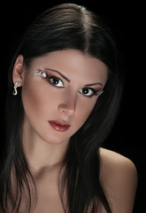 face of young woman with makeup on black background
