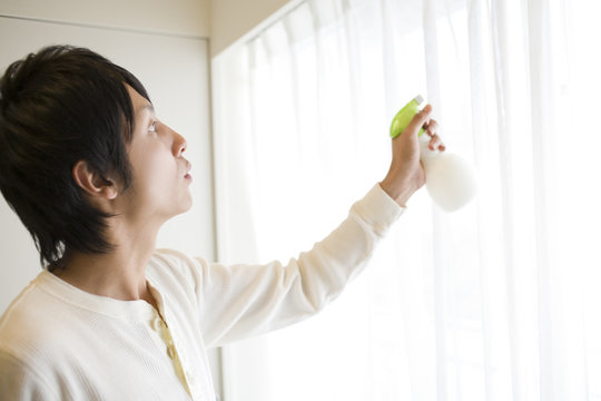 Man Spraying Deodorant Spray On Curtain