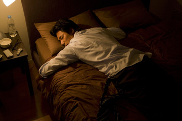 businessman sleeping on bed with suit worn