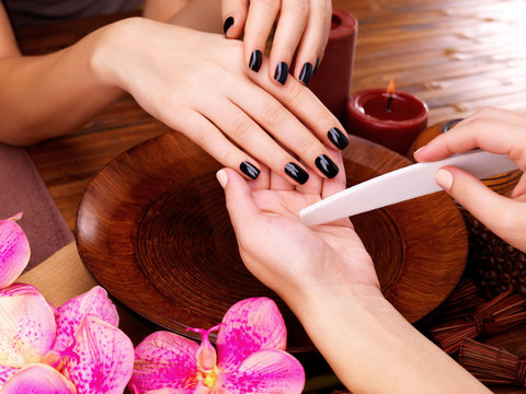 Manicurist master  makes manicure on woman's hands