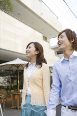 smiling couple walking in front of café