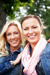 Two beautiful young women on a bench in a park