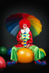 Clown auf Gymnastikball mit Regenschirm