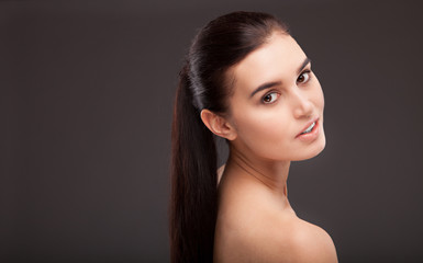 Portrait of a beautiful brunette woman on grey background. Fashi