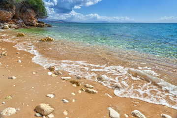 View to tide wave over pebbles and rocks on the sand