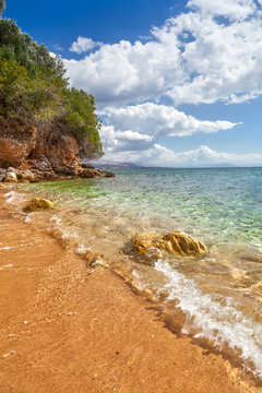 View to tide wave over pebbles and rocks on the sand