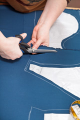 tailor cuts out dress according with pattern