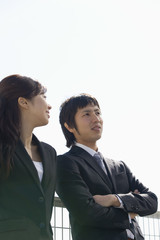 man and woman talking in front of fence