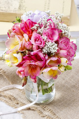 Bouquet of colorful freesia flowers in transparent glass vase.