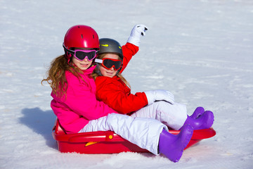 Kid girls playing sled in winter snow