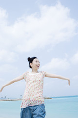 Fototapeta na wymiar smiling woman stretching arms under blue sky