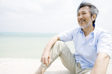 man sitting on beach looks at view