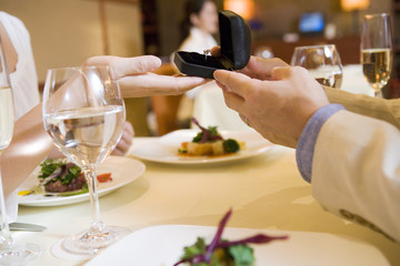 man giving woman a ring at restaurant