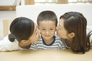 boy kissed by mother and elder sister