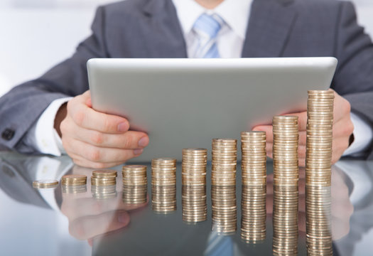 Businessman With Digital Tablet And Coin Stack