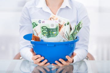 Businessperson Holding Hardhat With Banknote