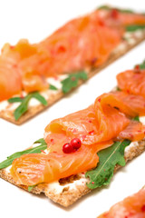 Salted salmon on crispy bread with cheese and arugula