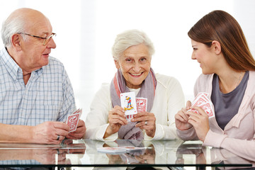 Senioren spielen Karten mit Sozialarbeiter