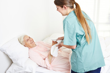 Krankenschwester wäscht eine bettlägerige Seniorin