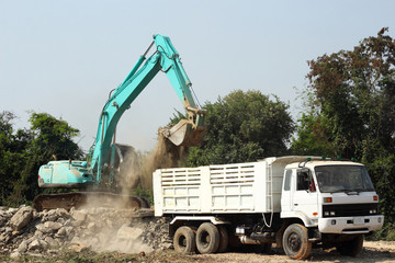 excavator loading stone dump truck on construction site