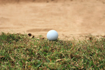 Golf ball on grass near sand  bunker