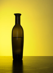 Backlit vintage olive oil bottle on counter. Brown glass.