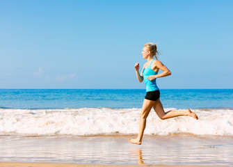 Fototapeta na wymiar Sporty blonde woman in sportswear jogging on a sunny beach