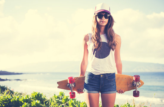 Hipster girl with skate board wearing sunglasses