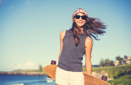 Hipster girl with skate board wearing sunglasses