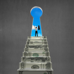 Man cheering on top of money stairs with key hole
