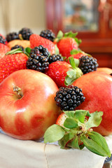 A basket filled with apples, strawberries, and blackberries