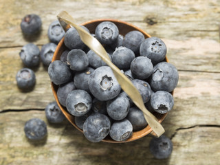 old basket with blueberries on wooden table, top view