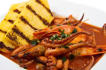 fish soup with grilled polenta on white dish