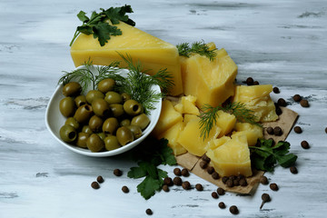 Parmesan cheese, fresh herbs and olives on wooden background
