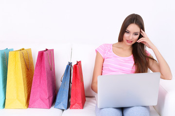 Beautiful young woman holding laptop with shopping bags