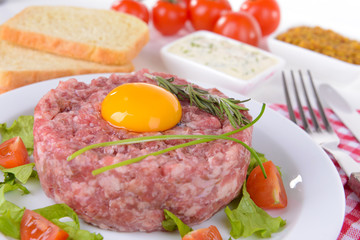 Delicious steak tartare with yolk on plate on table close-up