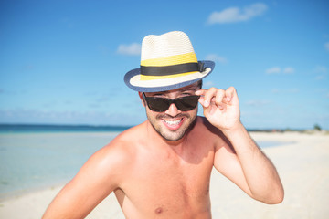 man on the beach taking off his glasses and smiles
