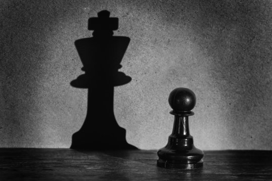 Chess pawn standing in a spotlight that make a shadow  actistic