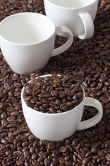 Drei Kaffeetassen, eine mit Kaffeebohnen gefüllt