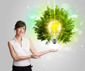 Young girl presenting idea light bulb with green tree