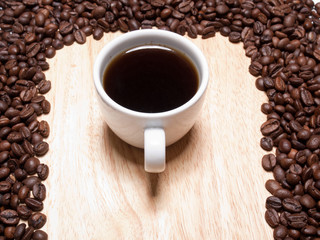 A cup of coffe on breadboard with coffee grains