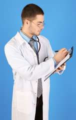 Male Doctor standing with folder, on blue background