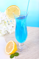 Glass of cocktail on table on light blue background