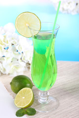 Glass of cocktail on table on light blue background