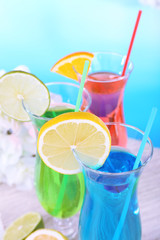 Glasses of cocktails on table on light blue background