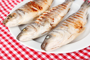 Delicious grilled fish on plate on table close-up