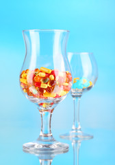 Goblets with pills on blue background
