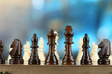 Chess pieces on board on bright background