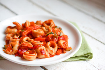 Tortellini primavera parmesan in marinara sauce on wooden rustic
