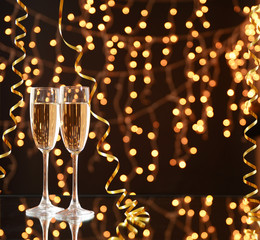 Glasses and bottle of champagne on shiny background